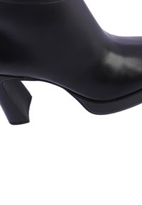 Botín de cuero negro hasta el tobillo con un acabado brillante, tacón cuadrado, textura suave y un diseño aerodinámico sin ningún hardware o patrones visibles.