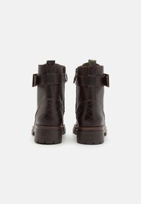 Bottines en cuir marron avec une finition texturée, motif matelassé sur les côtés, sangles à boucle et semelles robustes crantées.