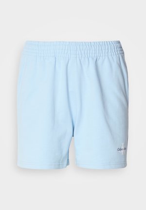 Heledad sinine lühike püksid elastse vööga, millel on "Calvin Klein" logo hemmi lähedal, esitatud neutraalses taustas.