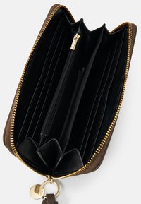 Brunt læderpung med en guldfarvet lynlås, flere kortlommer, en central lynlåslomme og en nøgleringdetalje. Indersiden har sort tekstureret foring.