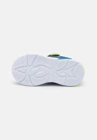 Valge kummist sneakerite tallad tekstuuriliste mustrite ja soontega. Omab siniseid ja neoonrohelisi aktsente ning on sileda pinnaga.