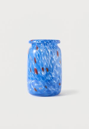 Bocal en verre bleu avec une lèvre arrondie, présentant un motif tacheté de points bleu foncé et rouges sur un fond blanc.