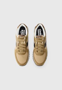Brown mesh and suede sneakers with a black accent, featuring flat laces, padded collar, and a textured rubber sole.