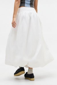 Gonna maxi bianca con vita smock, caratterizzata da una trama leggera e fluida. Abbinata a scarpe nere e calzini grigi chiari.