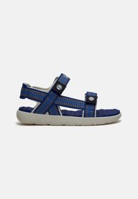 Sandale ajustable bleue et noire avec des sangles à motifs et une semelle blanche rembourrée, conçue pour une utilisation en extérieur ou décontractée.