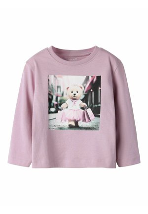 Light pink long-sleeve T-shirt featuring a graphic of a bear in a tutu, holding shopping bags. Soft cotton material with a round neck.