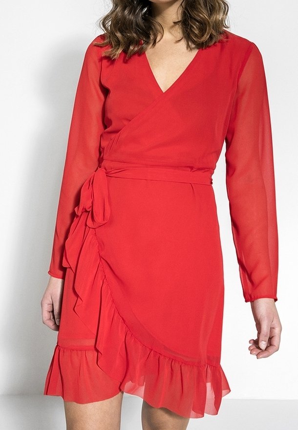 Vestido envolvente rojo con mangas largas de tela transparente, escote en V, cinturón en la cintura, bajo con volantes y textura de tela fluida.