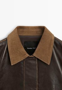 Veste en cuir marron avec un col en velours côtelé, dotée d'une fermeture éclair et d'une subtile brillance, portant l'étiquette "Massimo Dutti" à l'intérieur de l'encolure.