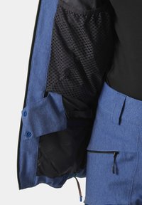 Blaue Jacke mit einem strukturierten schwarzen Innenfutter, Druckknöpfen und Taschen. Enthält eine glatte, leichte Außenlage.