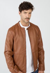 Braune Lederjacke mit glatter Textur, Reißverschluss und Druckknöpfen. Mit klassischem Kragen und seitlichen Taschen.