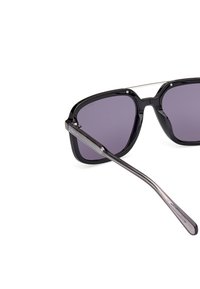 Ochelari de soare rectangulari cu rame întunecate, lentile gradient violet și brațe gri translucide, cu un logo de brand subtil.