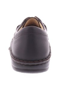 Bruine leren schoen, gladde textuur, ronde vorm, lage hak, gestikte details rond de zool, minimalistisch ontwerp met een klassieke uitstraling.