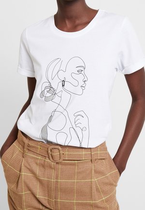 White t-shirt featuring a black line drawing of a woman's profile with abstract elements. Paired with brown plaid trousers with yellow accents.
