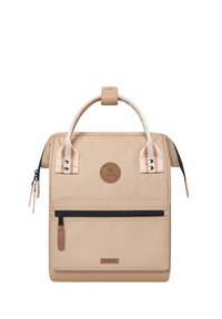 Sac à dos beige avec une poignée supérieure et une poche zippée à l'avant ; fabriqué en tissu durable avec des accents en cuir et un patch logo circulaire.