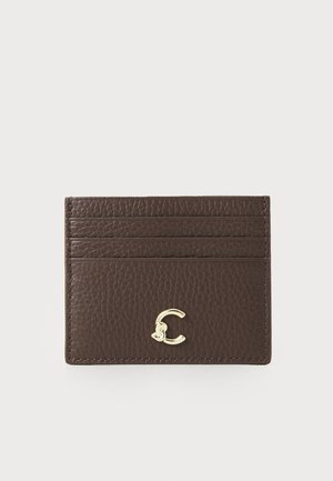 Brown leather cardholder with a textured finish, featuring four card slots and a gold-tone logo accent on the front.