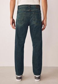 Mørke denimjeans med lige pasform, der har to baglommene, kontraststik og et læderpatch på taljebåndet.