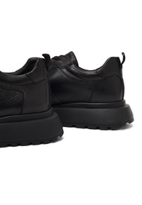 Sneaker nere in pelle con pannelli testurizzati, una spessa suola in gomma nera e linguette sul tallone per una facile calzata.