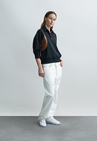 Musta pusero, valkoiset leveälahkeiset farkut, valkoiset lenkkarit, ruskea olkalaukku. Sileät materiaalit, rento istuvuus, rento muotoilu. Minimalistinen tyyli.