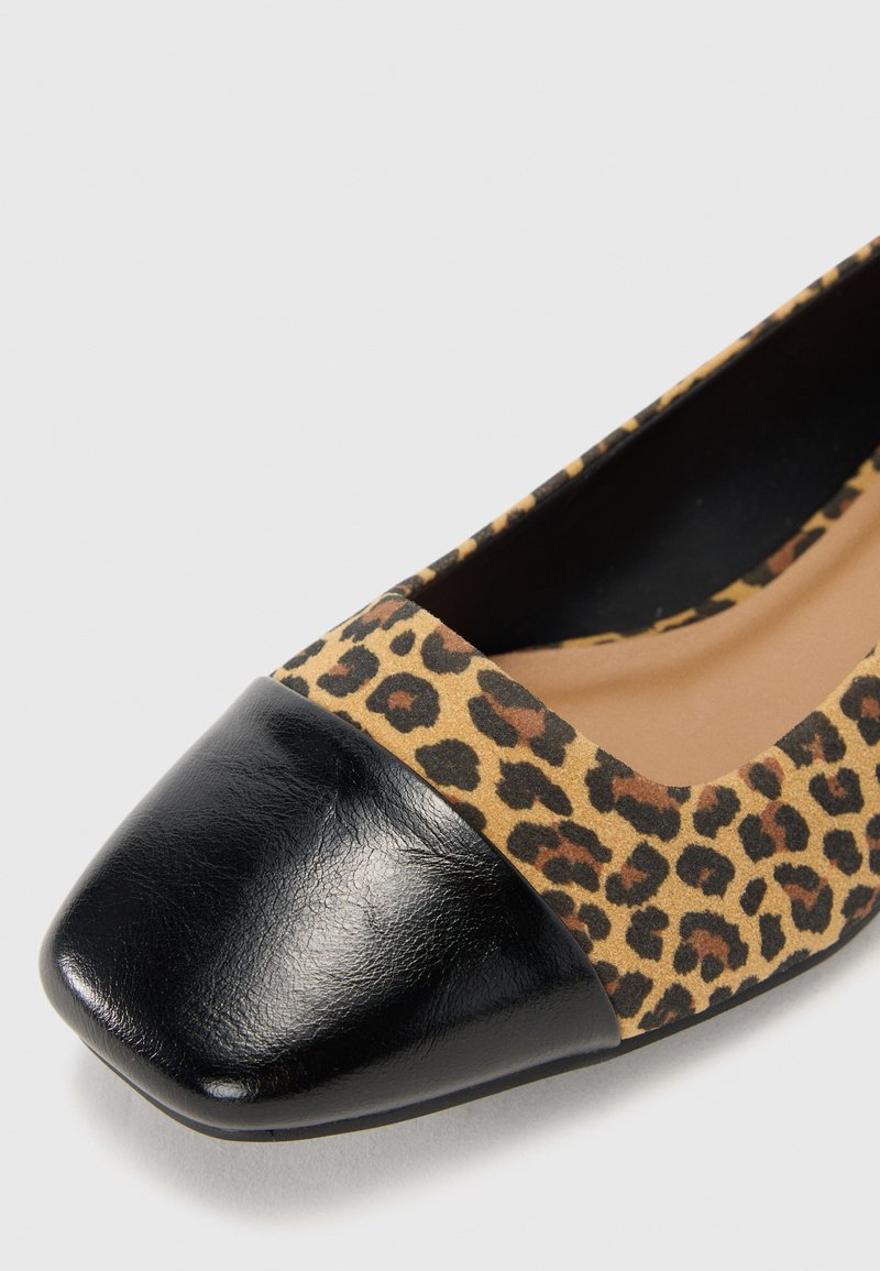 Zapato plano de estampado de leopardo con una puntera de charol negro, que presenta una textura suave y una forma redondeada para un ajuste cómodo.