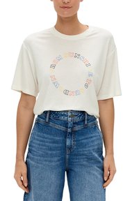 Ecru katoenen t-shirt met korte mouwen, voorzien van meerkleurige tekst in een cirkelvormig ontwerp die "VAN ZONOPGANG TOT ZONSONDERGANG" leest.