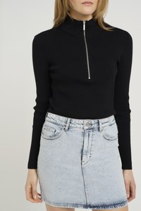 Maglietta nera a coste con maniche lunghe, colletto alto e zip frontale, abbinata a una minigonna in denim blu chiaro con tasche frontali.