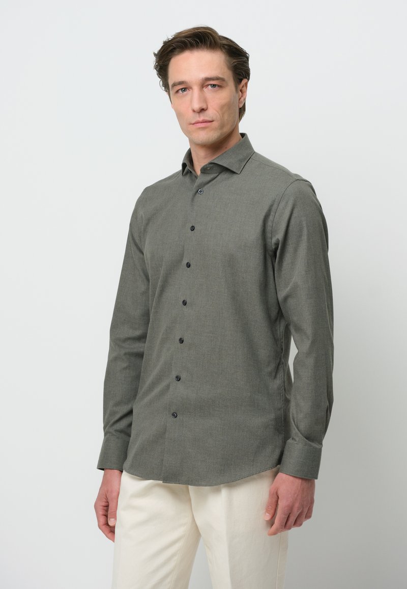Donkergroene lange mouw shirt met een button-down kraag, geweven stof en zwarte knopen, gecombineerd met lichtgekleurde broeken.