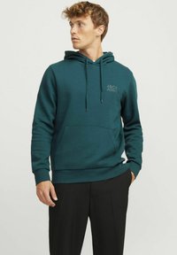 Capuchon sweatshirt in diep teal, van katoenmix. Kenmerkt een kangoeroezak, ribbelmanchetten en een gedrukt logo op de borst. Soepele textuur.