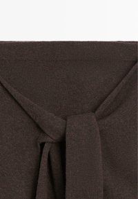 Brown knitted top featuring a tie detail at the neckline, with a soft texture and a smooth finish. Clean edges and no visible patterns.