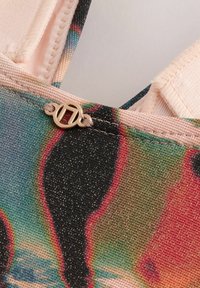 Tessuto colorato con design astratto in tonalità teal, nero e rosa. Presenta una superficie liscia e una chiusura decorativa in tono oro.