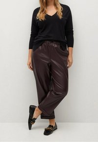 Czarny sweter w serek, zestawiony z bordowymi spodniami wide-leg z faux skóry, z troczkiem i zapięciem na guziki, uzupełniony czarnymi loafersami.