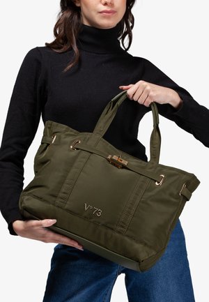 Olijfgroene nylon draagtas met gouden accenten, dubbele handvaten en een sluiting met haak. Heeft een gegraveerd logo aan de voorkant.