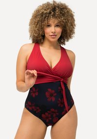 Maillot de bain rouge à encolure halter avec un détail drapé, présentant un bas marine orné de motifs floraux rouges. Texture lisse dans l'ensemble.