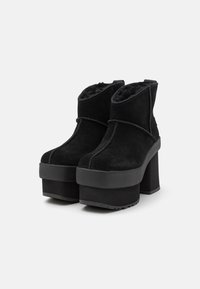 Bottines en daim noir avec une semelle plateforme épaisse. Présentent une tige texturée et un embout arrondi. Intérieur doublé d'un matériau doux pour la chaleur.