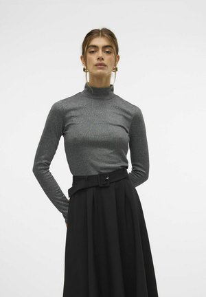 Haut col roulé gris à côtes associé à une longue jupe noire avec une taille ceinturée. La texture est lisse et élégante, avec une silhouette ajustée.