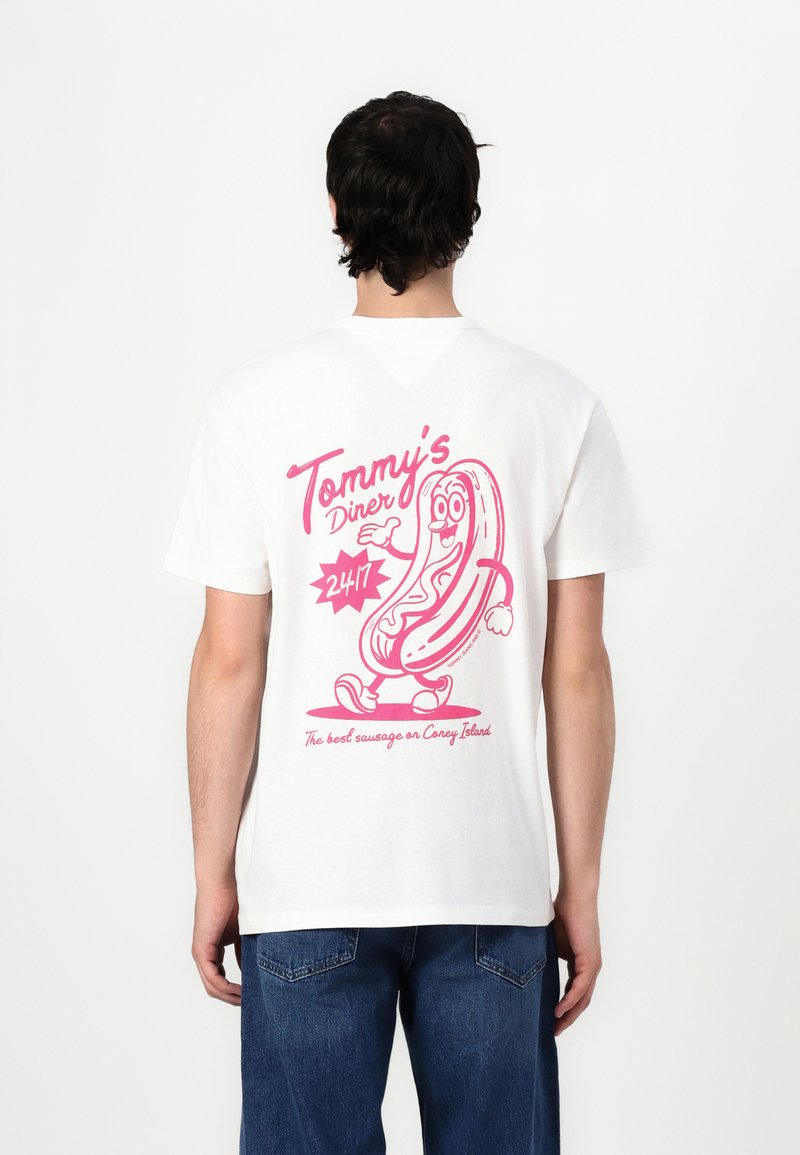 White cotton t-shirt featuring a large pink graphic of a cartoon hot dog and the text "Tommy's Diner 24/7" with additional slogan below.