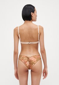 Brun blomstret bikini med tynne, justerbare stropper; bakdelen har subtil rynkning og en lukking med clasp. Mønsteret inkluderer rosa og grønne detaljer.