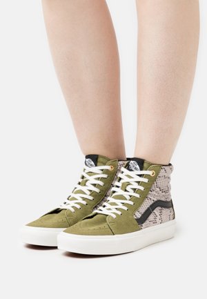 Baskets montantes en daim vert avec des accents texturés beige, des lacets blancs, un logo noir et une semelle en caoutchouc blanche.