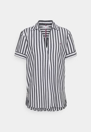 Chemise à manches courtes avec des rayures verticales noires et blanches, col ouvert et petit logo sur la poitrine gauche sur fond blanc.