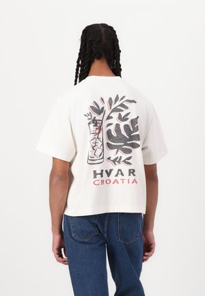 White short-sleeve t-shirt featuring a graphic of a cocktail glass with leaves, "HVAR" and "CROATIA" printed below in black and red.