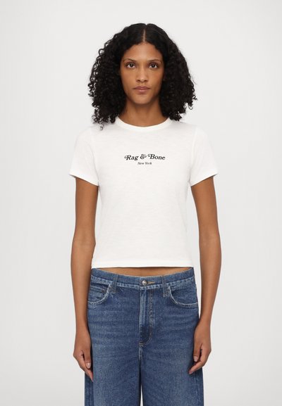 Λευκό κοντομάνικο cropped t-shirt με λαιμόκοψη crew, διαθέτει μαύρο κείμενο "Rag & Bone New York" τυπωμένο μπροστά. Συνδυάζεται με μπλε τζιν.