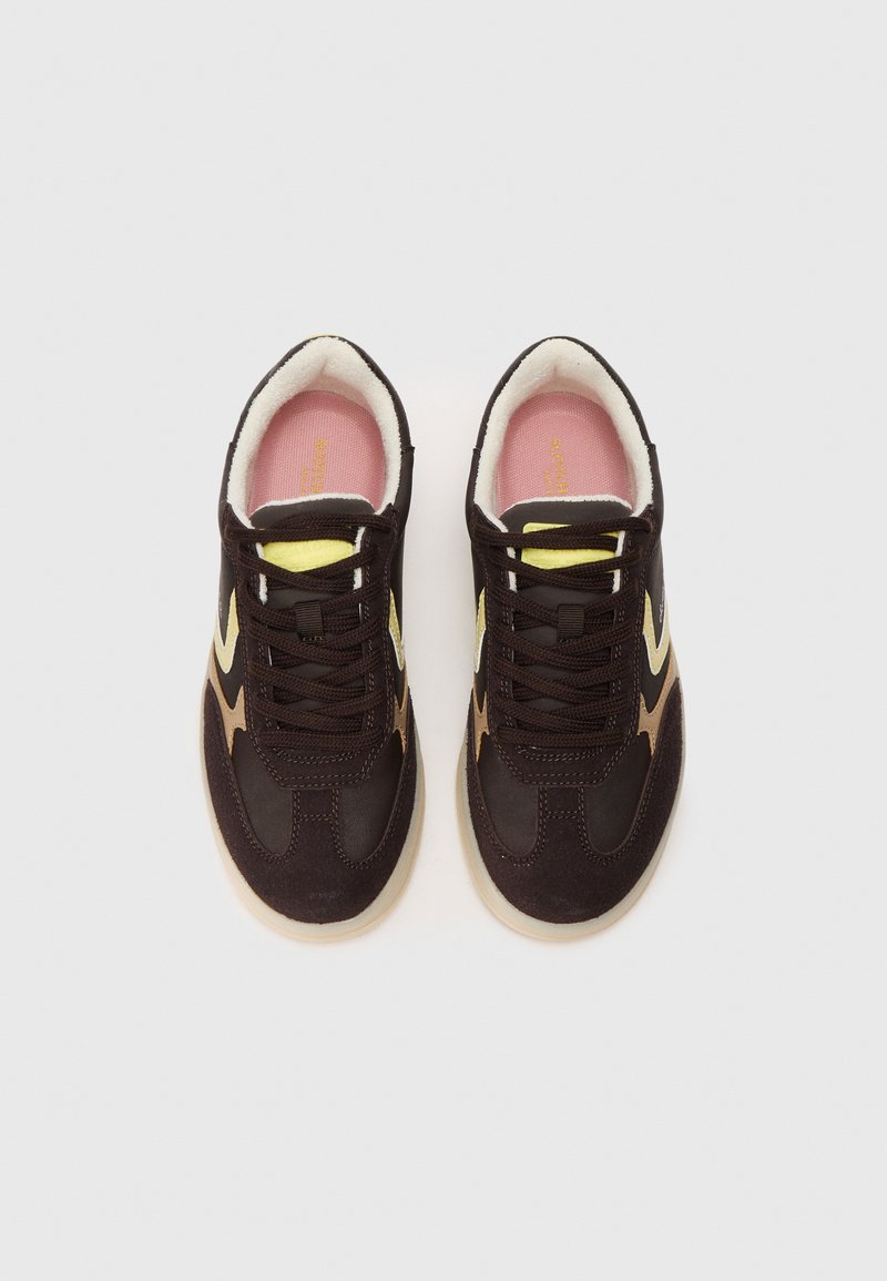 Baskets en daim marron avec des accents jaunes et crème, finition texturée, design à lacets, doublure intérieure douce et semelle en caoutchouc. Semelle intérieure rose visible.