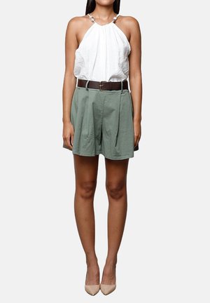 Top blanco sin mangas con diseño de cuello halter y detalle fruncido, combinado con pantalones cortos plisados verdes y un cinturón marrón. Tacones altos en tonos neutros.