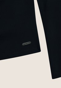 Maglietta nera a maniche lunghe con una forma aderente, realizzata in tessuto liscio. Presenta un logo metallico "FREDDY" sull'orlo, design minimalista.