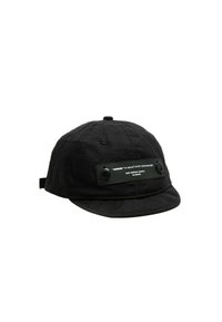 Gorra negra hecha de tela texturizada, con visera plana, detalles en botones y una etiqueta rectangular en la parte frontal con texto en blanco.