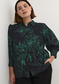 Hemd mit Kragen und Knopfleiste in dunkelblau mit grünem Blumenmuster, mit gerafften Ärmeln und lässigem Schnitt. Glatte Stofftextur.