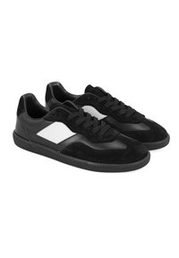 Schwarze Sneaker aus einer Kombination von Wildleder und Leder, mit einem weißen Mittelteil, strukturierten schwarzen Gummisohlen und klassischem Schnürdesign.