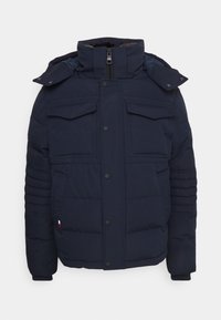 Mörkblå vadderad jacka med hög krage, två stora bröstfickor, två sidofickor och ribbade ärmender. Stängs med knappar.
