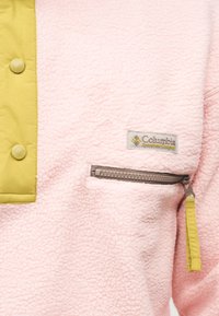 Μαλακό ροζ φλις μπουφάν με κουμπιά και φερμουάρ σε μουσταρδί κίτρινο, με ετικέτα λογότυπου της Columbia Sportswear Company.