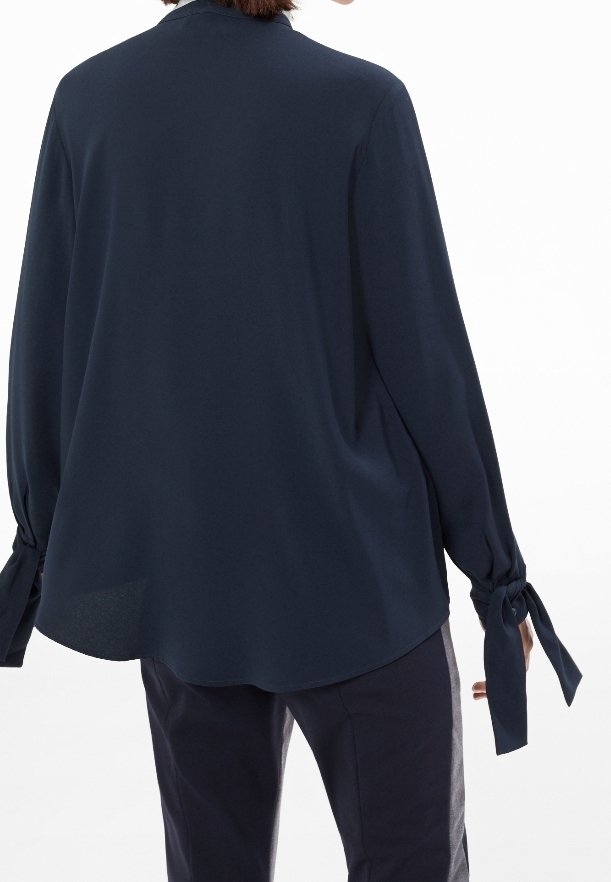 Mörkblå blus med en lös passform, långa ärmar som är knutna vid handlederna och rundad nederkant. Tillverkad av ett mjukt, lätt material.