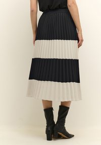 Plisovaná midi sukně s střídavými pruhy v černé, tmavě šedé a béžové barvě. Elastický pas, doplněná černými kozačkami po kolena.